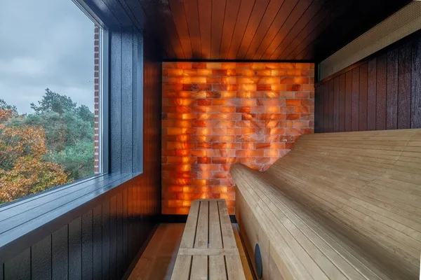 Salzsteinsauna mit leuchtender Wand aus Salzsteinen und Fenster zu den Baumkronen